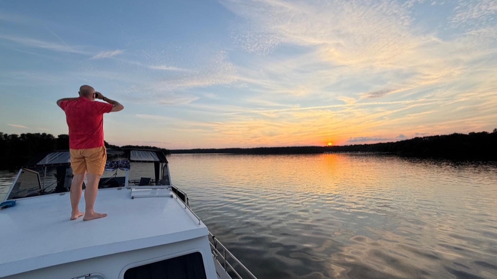 Person auf einer Motoryacht bei Sonnenuntergang auf einem Binnengewässer